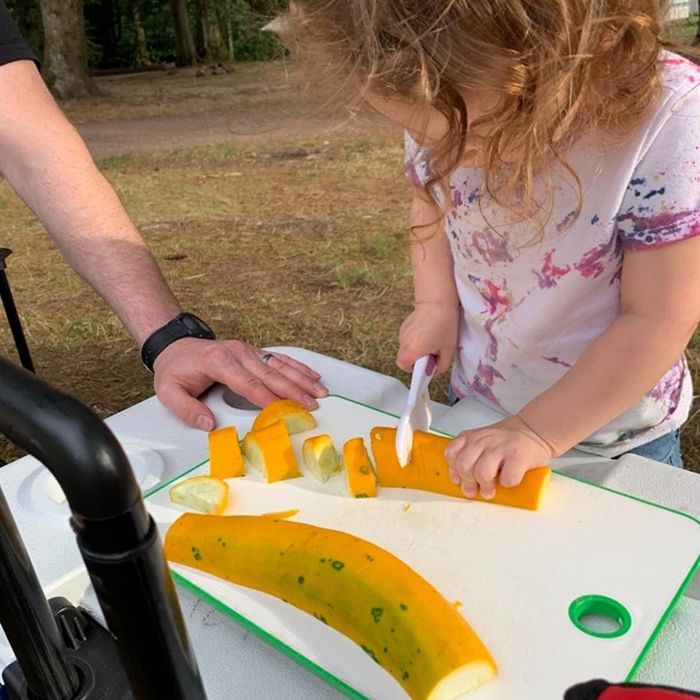 A child slicing a squash with the plastic knife