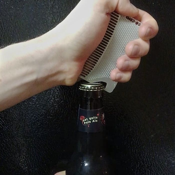 A sleek, credit card-sized metal comb with a curved edge used to effortlessly open a bottle.