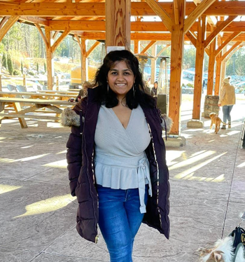Reviewer layering a light grey wrap sweater under a jacket, paired with jeans
