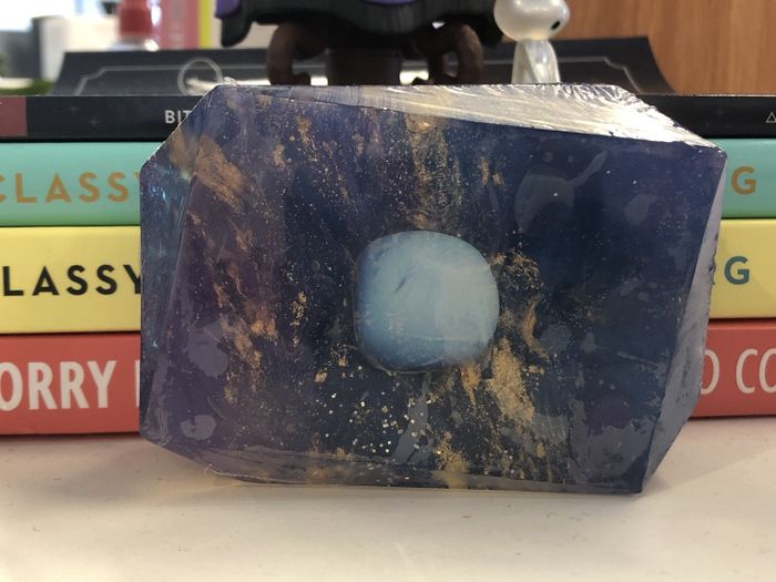 A stone-like purple soap bar with a healing crystal in its center.