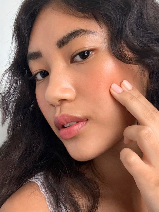 A model gently applying the blush using two fingers