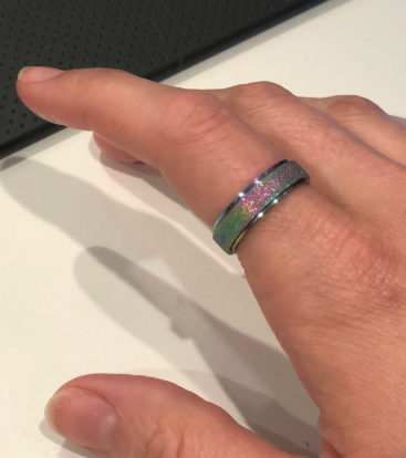 A shimmering iridescent version of the ring, showcased on a reviewer's finger.