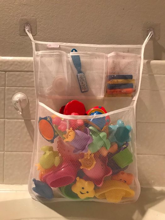 A reviewer’s photo showing a mesh organizer with bath toys, securely stuck to the wall.