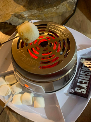 A reviewer toasting a marshmallow on a campfire