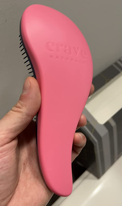 reviewer's image showcasing the ergonomically designed brush in a pink color