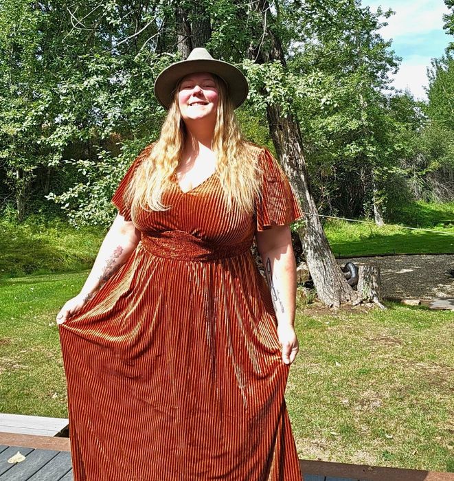 The reviewer is wearing a burnt orange dress.