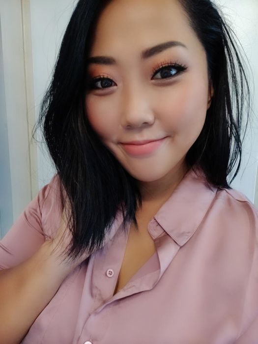 An Asian reviewer showcasing a light pink blush on their cheeks