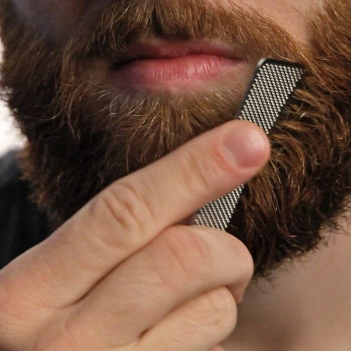 A model using a comb to tidy up their beard.
