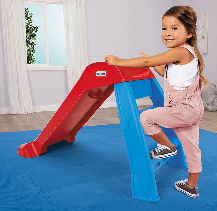 A child playing on an orange and blue Little Tikes slide