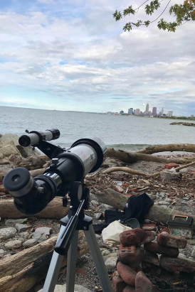 A reviewer's telescope set up on a beach, aimed at a distant skyline.
