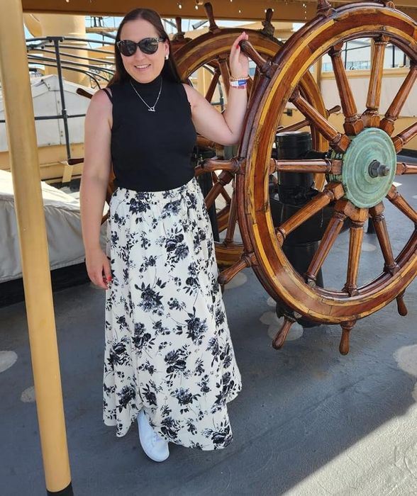 The reviewer is wearing a black and white floral skirt.