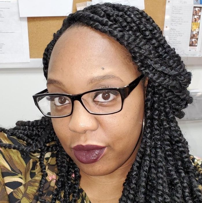 A reviewer models a bold dark purple lipstick, showcasing its rich and striking color.