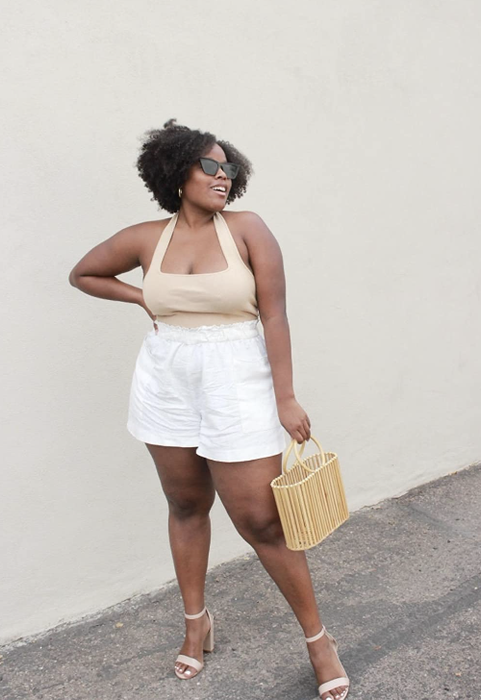 The reviewer is wearing a top paired with white shorts and heels.
