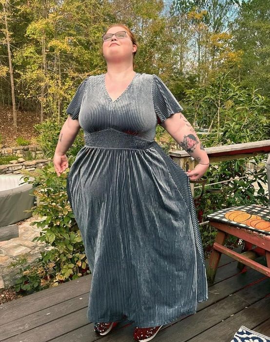 The reviewer is wearing a blue-gray dress.