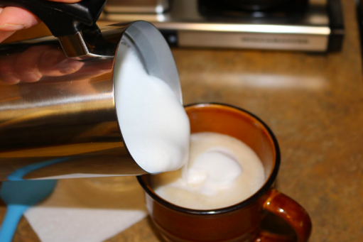 The reviewer skillfully pouring froth into their drink.