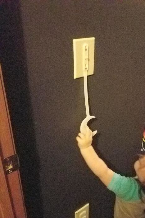 A reviewer's photo of a child trying to reach the light switch extender