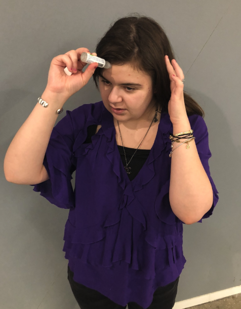 Mytour writer applying the migraine relief stick to her forehead