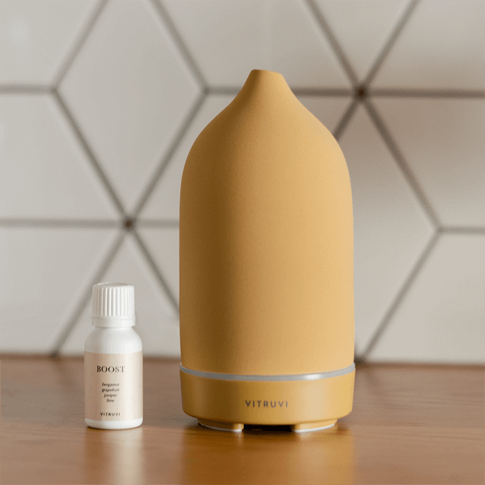 A matte yellow stone diffuser paired with a bottle of essential oils.
