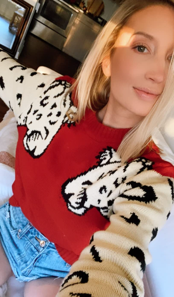A reviewer is seen wearing the sweater in a vibrant red, adding a bold pop of color to the outfit.