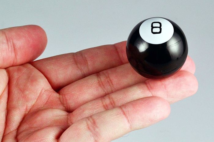 A model balancing a tiny magic 8 ball on the tip of their finger