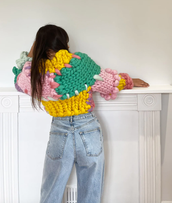 A model shows off the back of the same sweater paired with jeans.