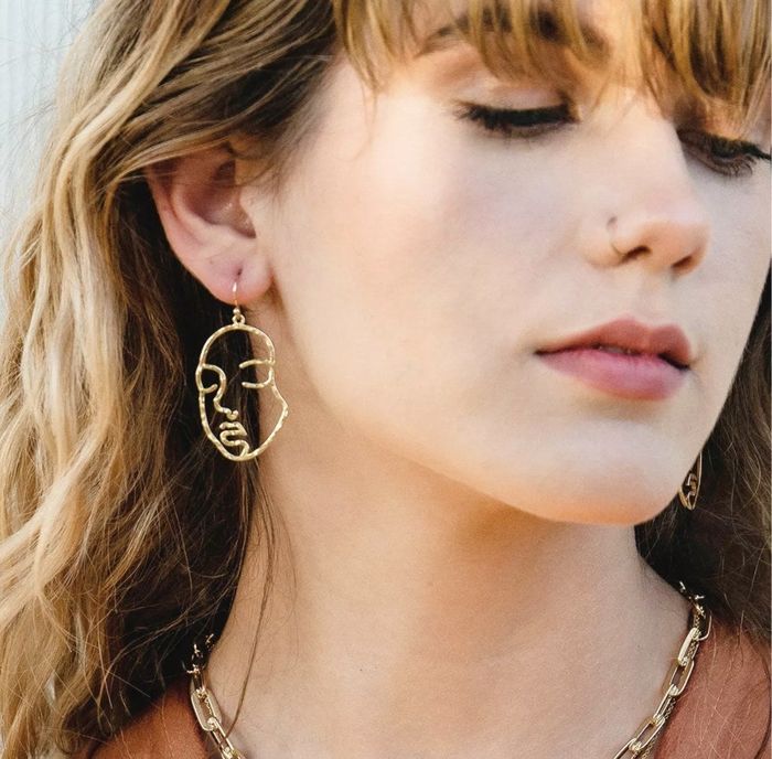 A model showcasing the face-shaped earrings