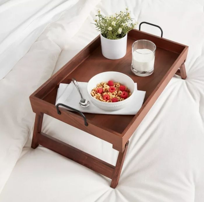 The wooden serving tray with breakfast on top in bed