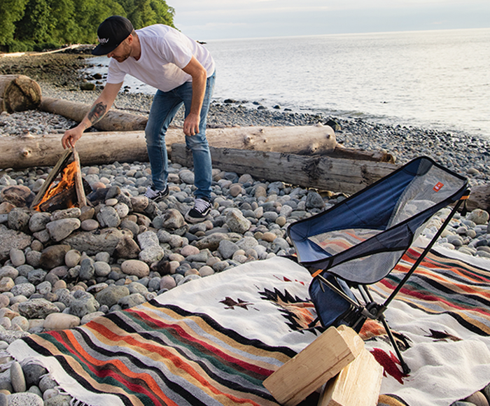 The navy camp chair resting on a blanket at a campsite, ready for use.