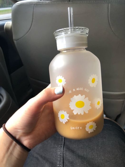The reviewer is holding a glass bottle filled with iced coffee.