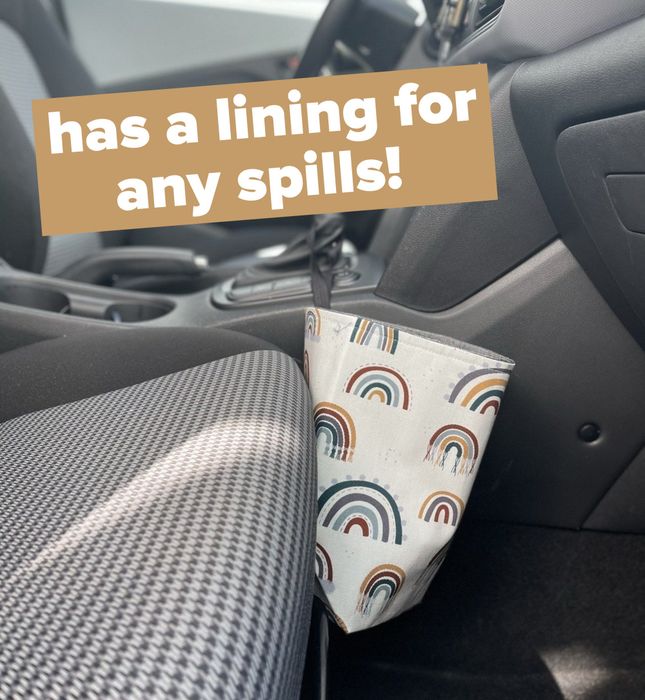 A boho rainbow-patterned trash can that's conveniently hooked onto a gear shift for easy access in the car.