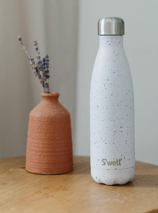 A white water bottle with black speckles adorning it.