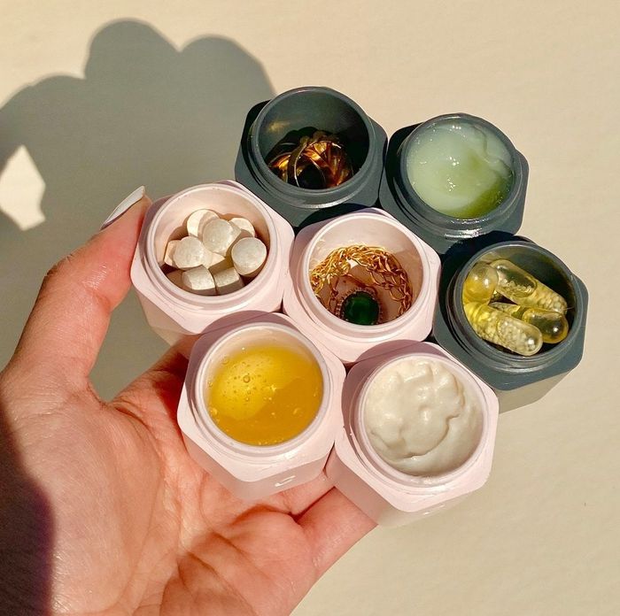 A hand gripping the hexagonal containers, each filled with different items