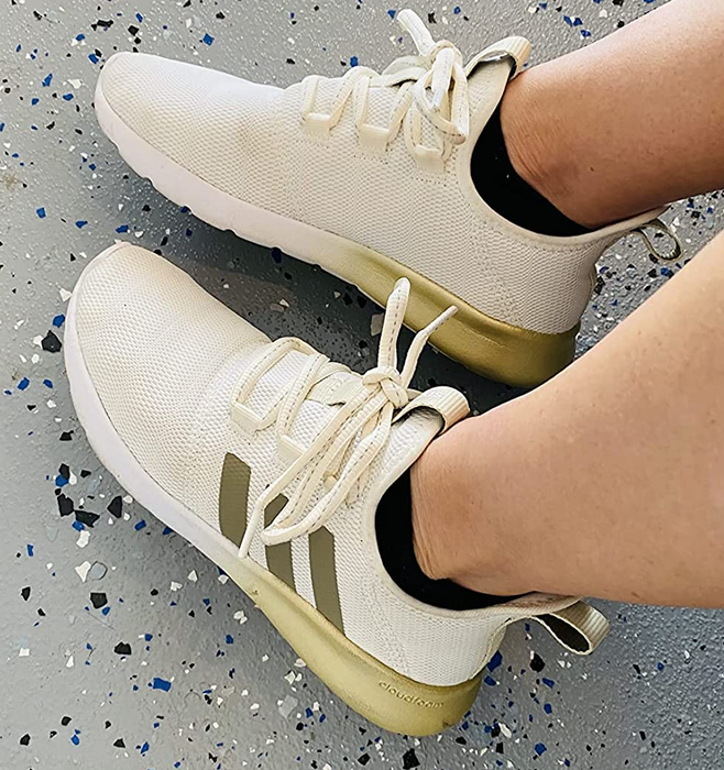 a reviewer wearing white sneakers with metallic gold accents