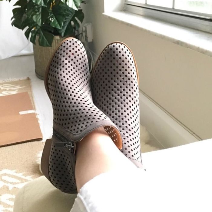 A reviewer models the boots in gray with perforated details.