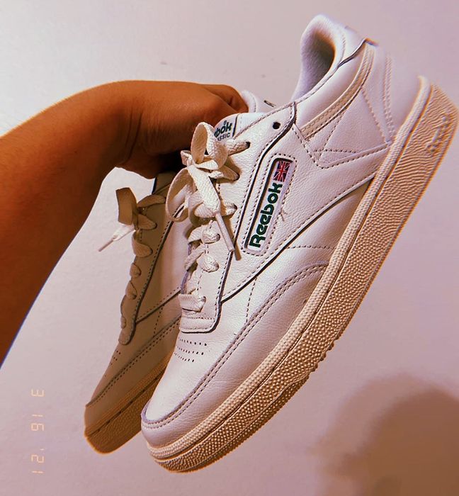 a reviewer showing off the off-white sneakers with a green Reebok label