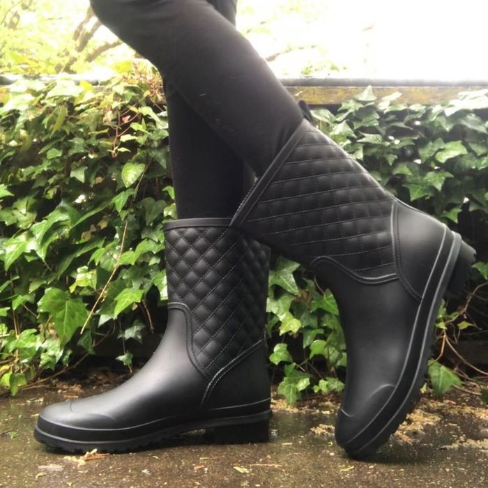A reviewer shows someone wearing black leggings and the rain boots outdoors.