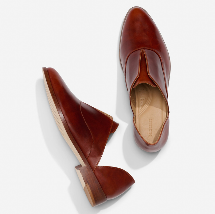 Two brown leather Oxford shoes, one shown from the side and the other from above, resting on a white backdrop.