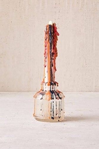 A candle after burning, with colorful rainbow drops gracefully dripping down its sides.