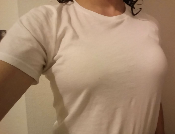 A reviewer wearing a white t-shirt with no visible bra beneath it.