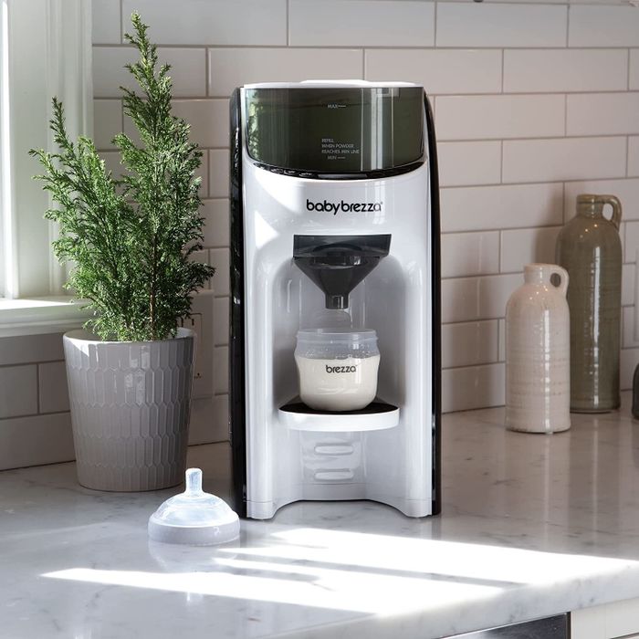 A baby bottle being prepared in the sleek white and black Baby Brezza formula dispenser machine.