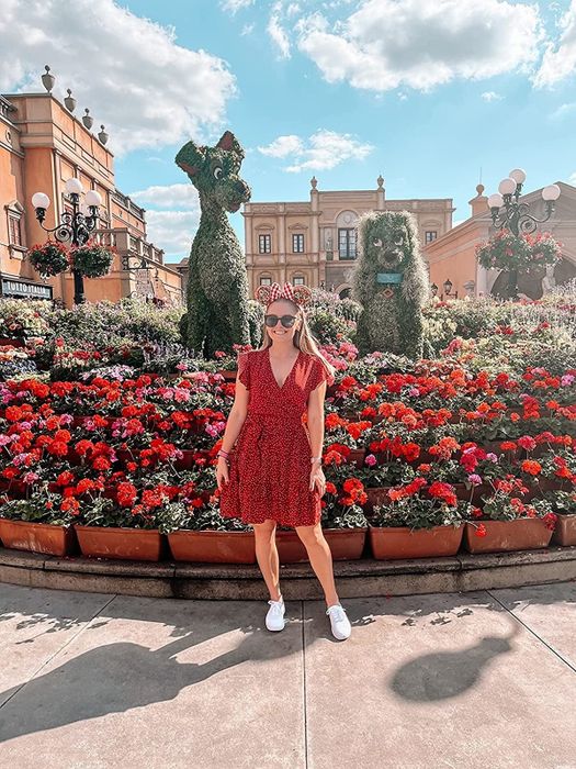 A reviewer is dressed in a red polka dot ruffle cap-sleeve dress.