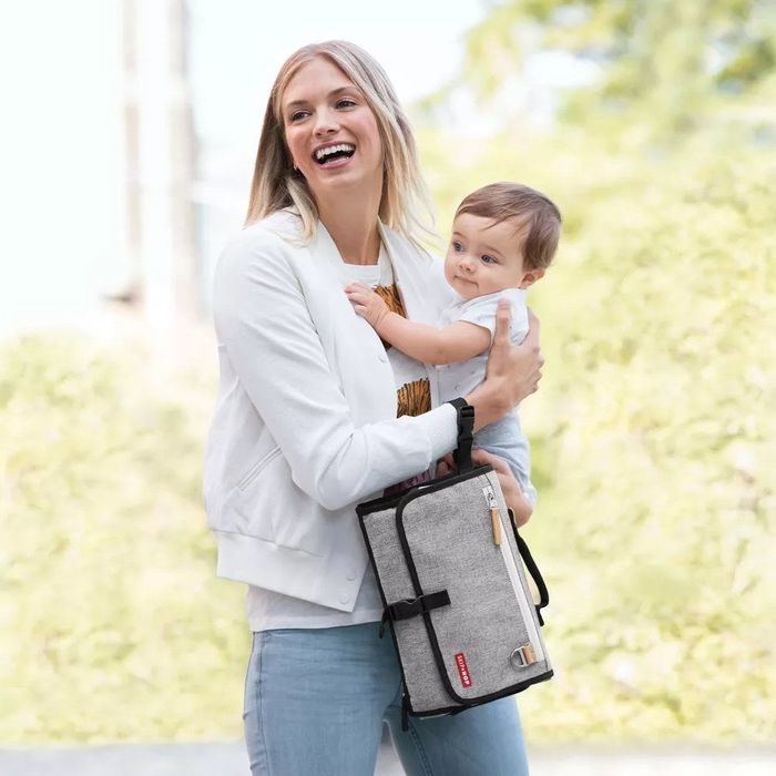 A diaper clutch folded neatly and worn around a model's wrist.