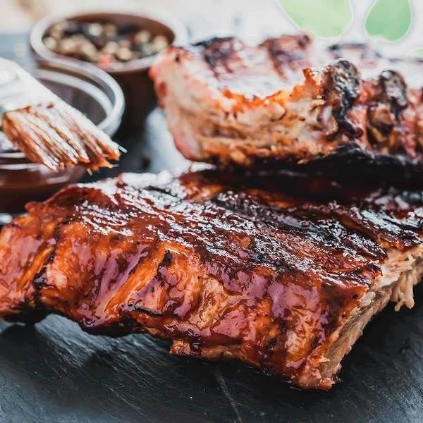 A close-up shot of barbecue ribs, generously slathered in rich, flavorful sauce.