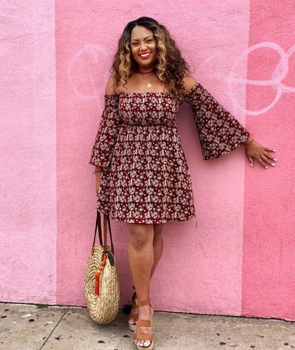 A reviewer shows off the maroon off-the-shoulder ruched mini-dress.