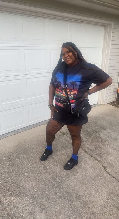 A reviewer is wearing a black graphic t-shirt dress.