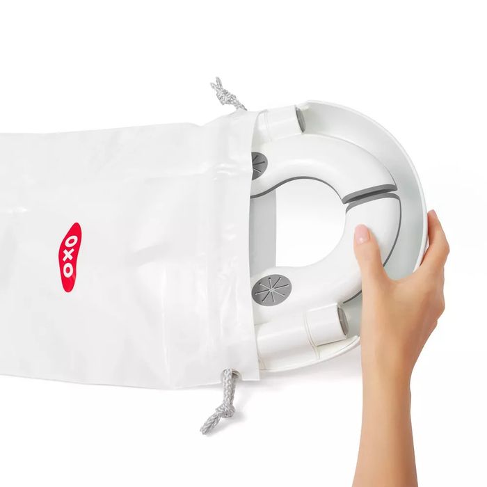 A hand placing a white, round device into a plastic storage bag with a red and black logo.