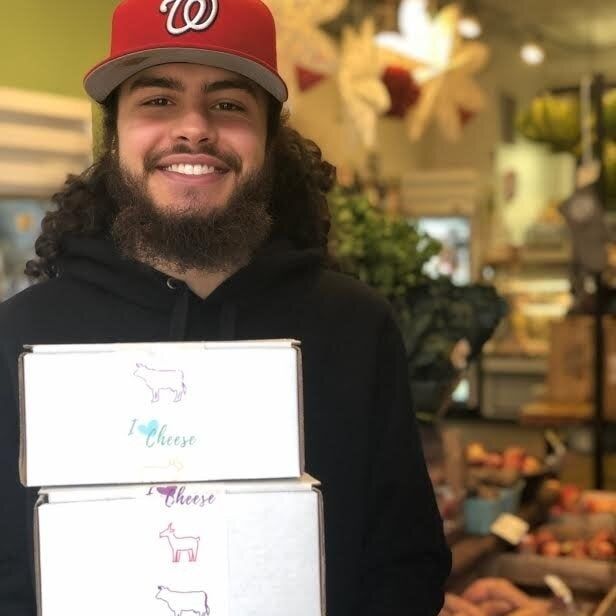 A photo showing an employee holding a stack of cheese subscription boxes.