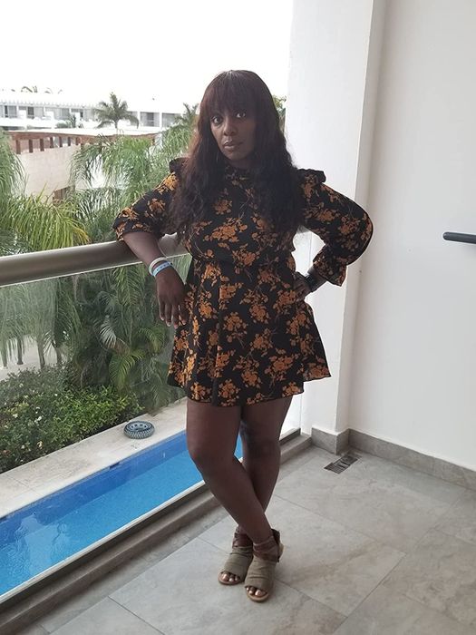 A reviewer is wearing a chic black multi-colored mock neck long-sleeve dress.