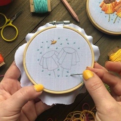 A pair of hands at work, embroidering a design onto an embroidery hoop.