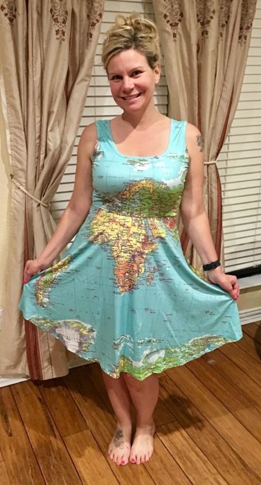 A reviewer is wearing a green map print sleeveless midi-dress.